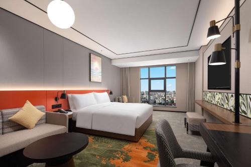 a hotel room with a bed and a couch at Hilton Garden Inn Beihai Jiafu in Beihai
