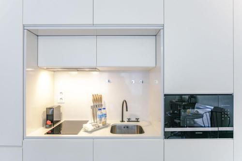 a kitchen with white cabinets and a sink at Door 65 - Historical Center Apartments in Porto