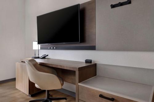 a desk with a chair and a television on a wall at Hyatt Place Flagstaff in Flagstaff