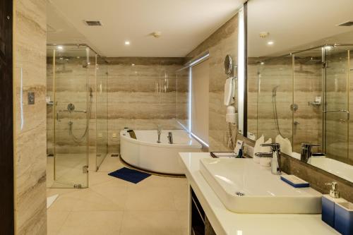 a bathroom with a tub and a sink and a shower at Olive Downtown in Cochin