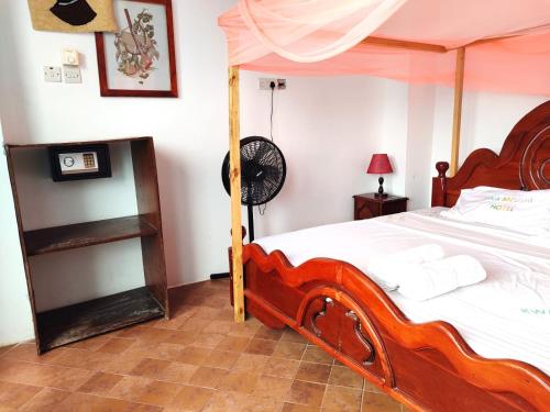 a bedroom with a large wooden bed with a fan at HOMELAND SWAHILI LODGE Nungwi Backpacker Apartments BUDGET in Nungwi