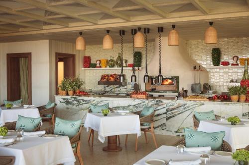 a restaurant with white tables and chairs and a fireplace at Royal Mansour Tamuda Bay in M'diq