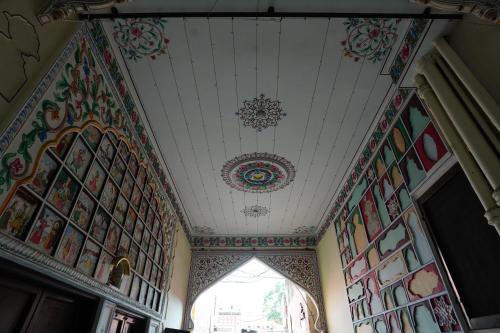 a room with a ceiling with paintings on it at Haveli Kalwara - A Heritage Hotel in Jaipur