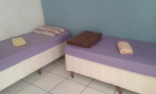 two beds in a room with purple and purple sheets at Pousada Aloha in Santos