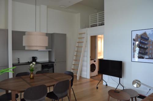a living room with a dining room table and a kitchen at Hotel Lille Nyhavn in Skanderborg