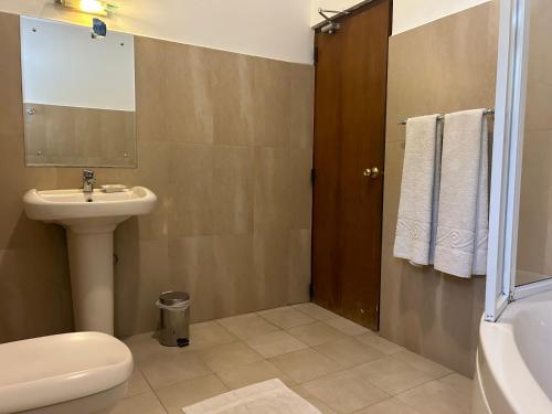 a bathroom with a sink and a toilet and a mirror at Occazia Residence in Colombo