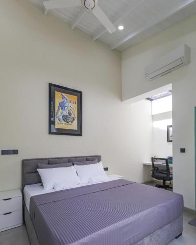 a bedroom with a bed with a purple comforter at Nomad Nest in Hikkaduwa