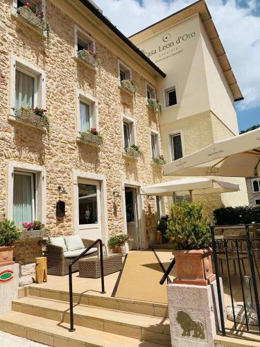 a large stone building with a patio and an umbrella at Casa Leon d'Oro in Bosco Chiesanuova