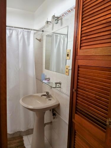 a white bathroom with a sink and a mirror at Vistas in Piriápolis