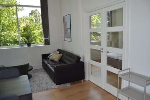 a living room with a black couch and windows at Hotel Lille Nyhavn in Skanderborg