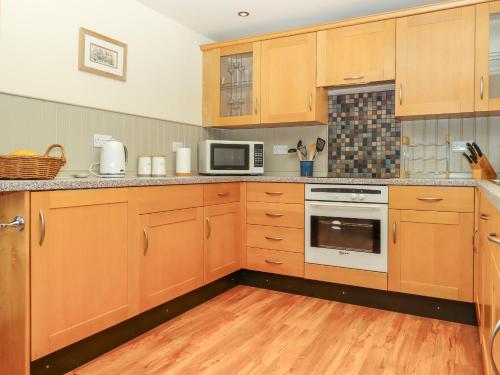 a kitchen with wooden cabinets and a stove top oven at Sherway Shippen in Cullompton