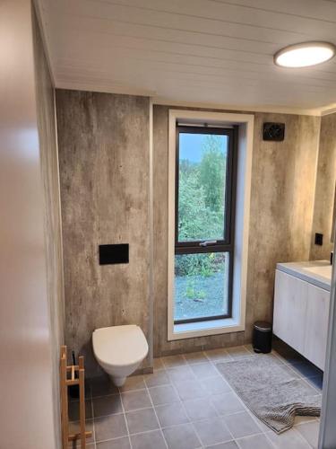 a bathroom with a toilet and a window at Nyoppført hytte med mulighet til å leie badestamp in Levanger