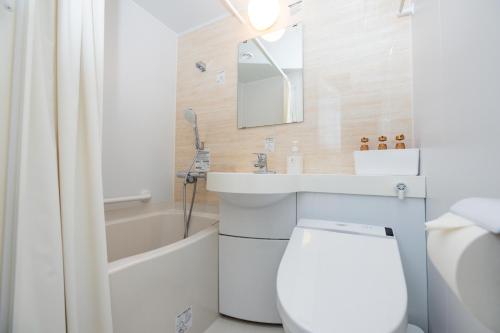 a bathroom with a toilet and a sink and a bath tub at Hotel Takasago in Kochi