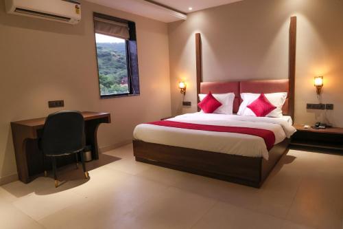 a hotel room with a bed and a desk and a window at Jaipur Qila - A Boutique Hotel and Rooftop Cafe in Jaipur