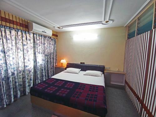 a bedroom with a bed in a room with curtains at Hotel Chetana in Dāvangere