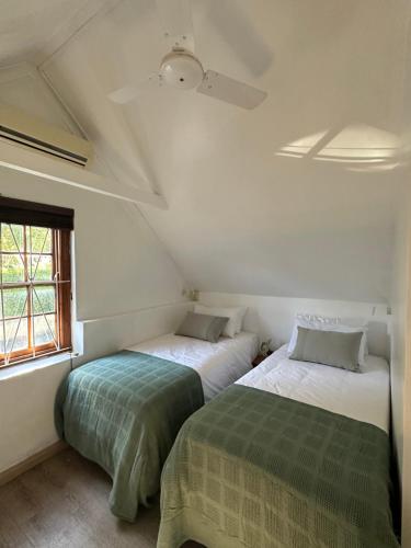 two beds in a small room with a window at Koetshuis on High Street in Paarl