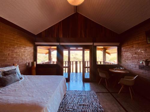 a bedroom with a bed in a room with windows at Refúgio dos pinhais in Sapucaí-Mirim