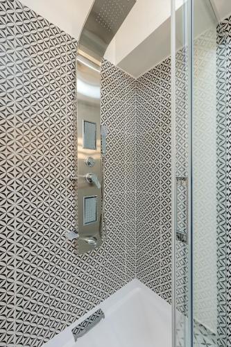 a bathroom with a shower with a tile wall at Bambusz Apartman with parking in Budapest