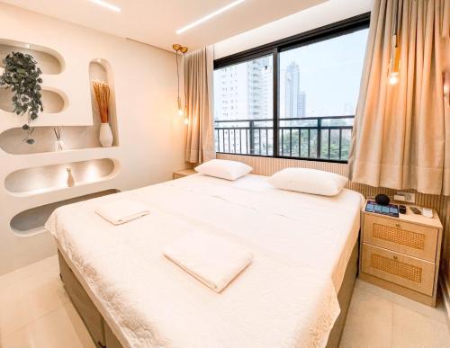 ein Schlafzimmer mit einem großen Bett mit einem großen Fenster in der Unterkunft Luxury Collection - Flat Ultra Luxo com 2 quartos in Campo Grande