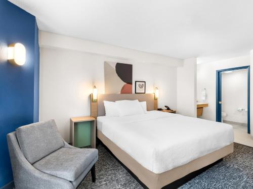 a bedroom with a white bed and a chair at Spark by Hilton Augusta in Augusta