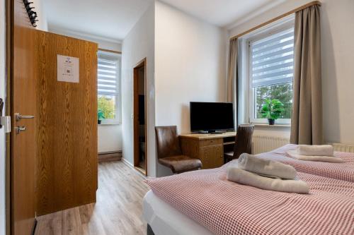 a bedroom with two beds and a tv and a window at Gruppenhaus Osterhagen in Bad Lauterberg