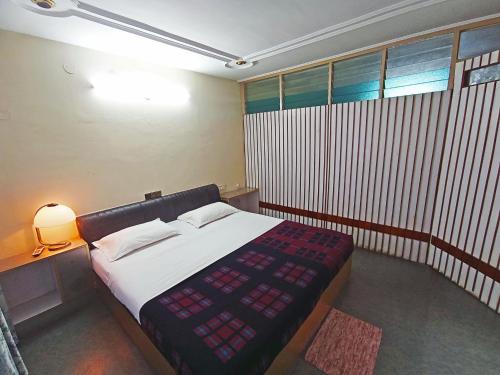 a bedroom with a bed and a table with a lamp at Hotel Chetana in Dāvangere