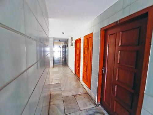 an empty hallway with orange doors in a building at Hotel Chetana in Dāvangere