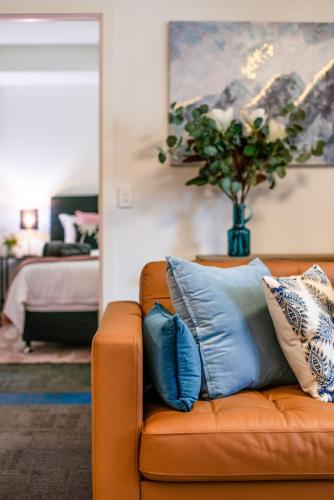 a living room with an orange couch with blue pillows at The Waymouth Executive I Workspace I Free Parking in Adelaide
