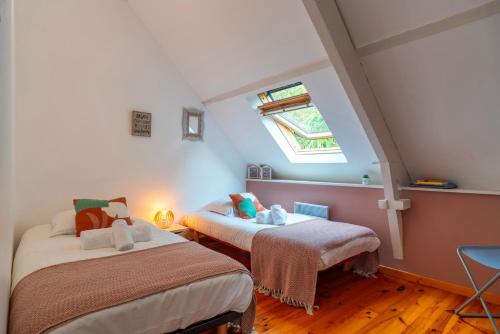two beds in a room with a window at La Libellule - Charmante maison avec jardin à Séné in Séné