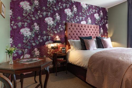 a bedroom with a large bed with a floral wallpaper at The Red Lion Hotel in London