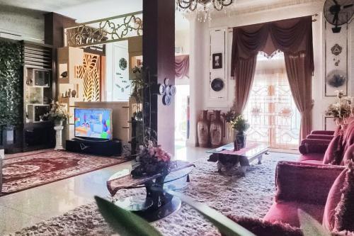 a living room with pink furniture and a large mirror at RedDoorz Syariah at Chilla Guest House Padang in Padang