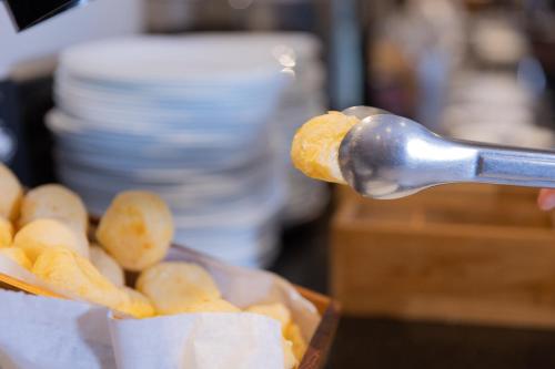 a person is holding a spoon with a basket of food at Hotel Lieto in Poços de Caldas