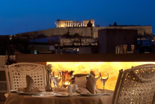 a table with chairs and wine glasses on a balcony at The Athenian Callirhoe Exclusive Hotel in Athens