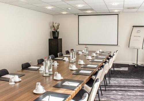 a conference room with a long table and a white screen at Amrâth Grand Hotel Frans Hals in Haarlem