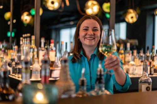 a woman sitting at a bar holding a wine glass at Motel One Berlin Mitte in Berlin