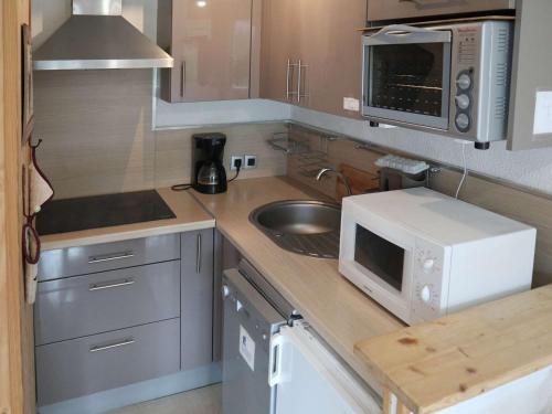une petite cuisine avec un évier et un micro-ondes dans l'établissement Bel appartement 2 pièces, skis aux pieds, pour 6 pers. - FR-1-322-356, aux Orres