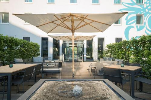 a patio with tables and an umbrella and a fountain at Motel One Hamburg Airport in Hamburg