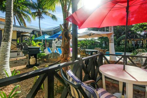 a balcony with a table and a red umbrella at Mary's Boon Beach Resort & Spa in Simpson Bay