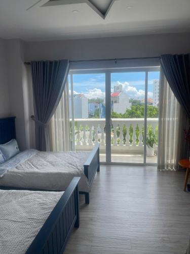 a bedroom with two beds and a large window at Homestay Ocean Real in Phan Thiet