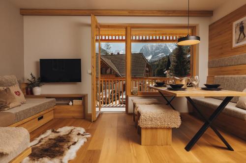 a living room with a table and a balcony at Goldhorn Chalet SKI IN&OUT in Kranjska Gora