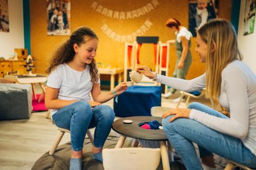 two young girls sitting in chairs in a room at Slow Travel Resort Kirchleitn in Bad Kleinkirchheim