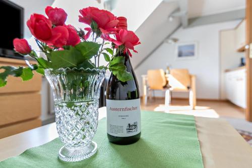 a bottle of wine and a vase of red flowers at Atlanta Pur in Pellworm
