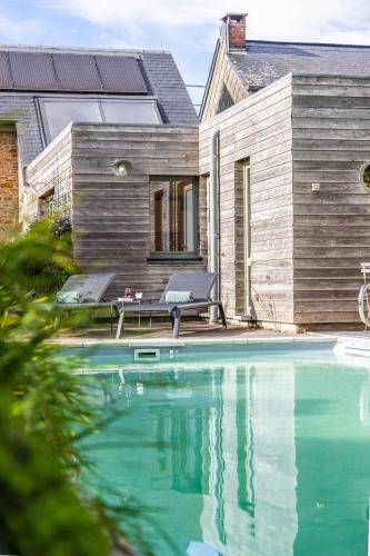 a house with a swimming pool in front of a house at LA PETITE EVELETTE - Piscine et Sauna au Calme in Ohey