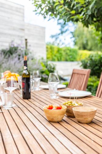 a wooden table with bowls of tomatoes and a bottle of wine at LA PETITE EVELETTE - Piscine et Sauna au Calme in Ohey