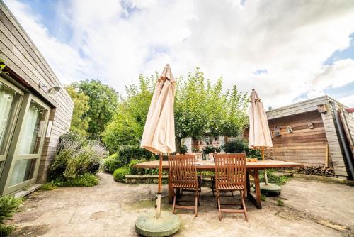 a wooden table with two chairs and an umbrella at LA PETITE EVELETTE - Piscine et Sauna au Calme in Ohey