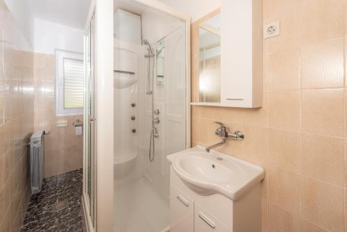 a white bathroom with a sink and a shower at Apartments Ivan in Novalja