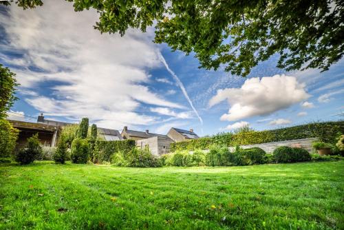 a grassy yard with a house and a blue sky at LA PETITE EVELETTE - Piscine et Sauna au Calme in Ohey