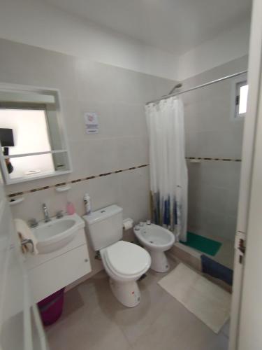 a white bathroom with a toilet and a sink at Camino 124 NQN in Neuquén