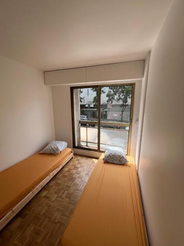 Cette chambre comprend deux lits et une grande fenêtre. dans l'établissement New Apartment in Paris, à Paris