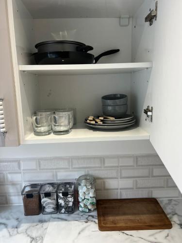 a cupboard with plates and bowls and a pot and pans at Town Centre En Suite Room 1 in Barnstaple
